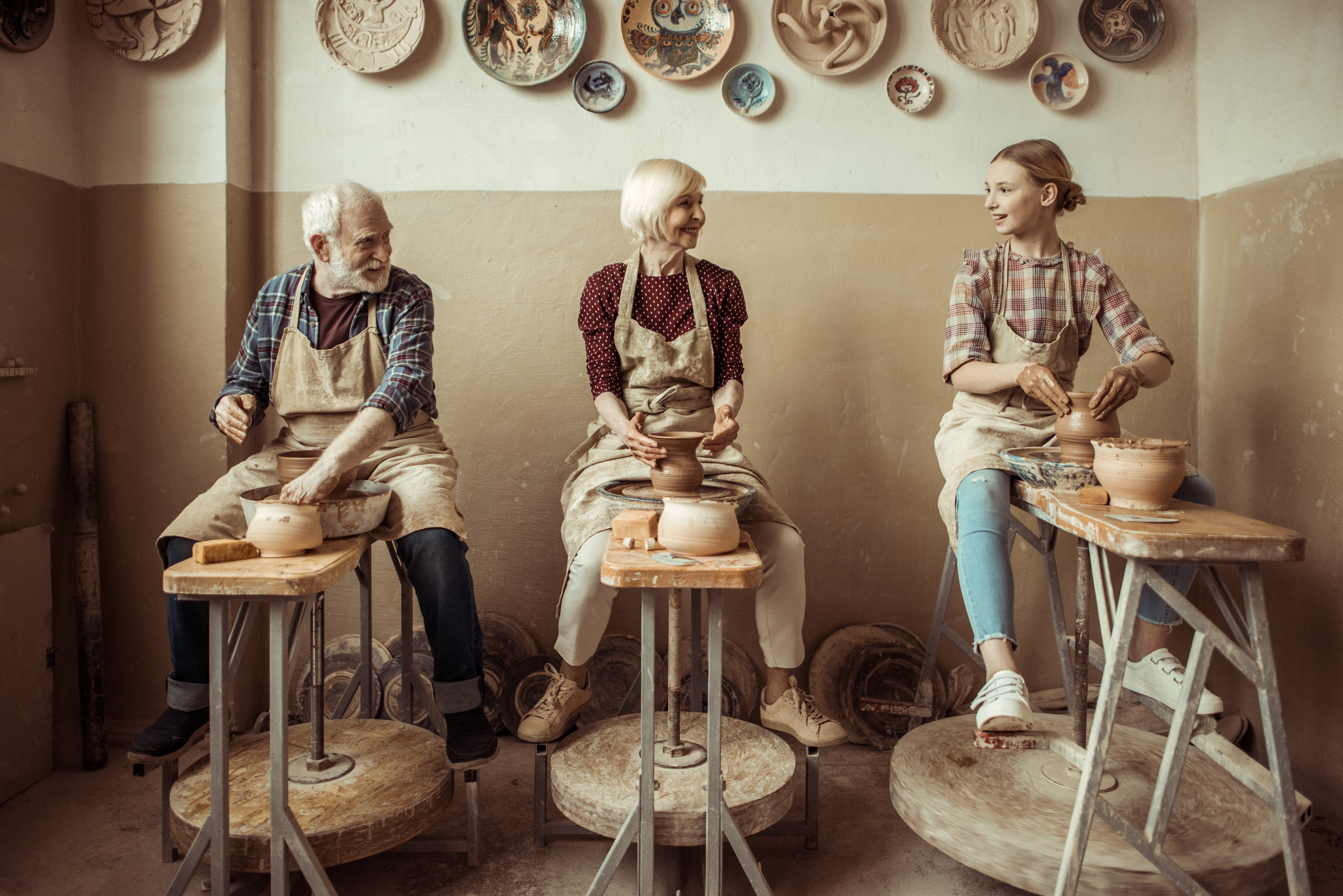 Grands-parents faisant de la poterie avec leur petite-fille dans un atelier